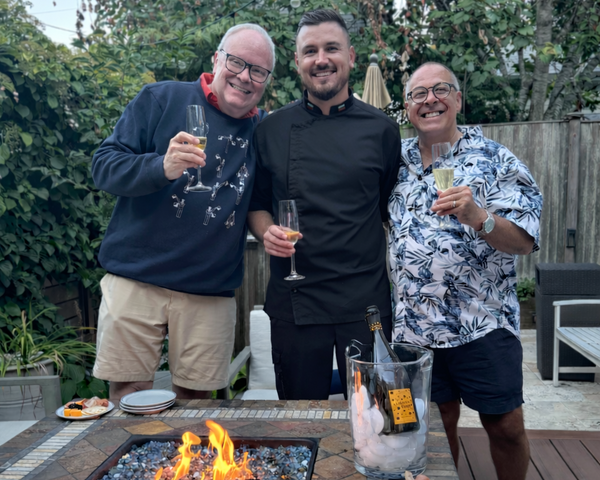 Private chef enjoying a outdoor gathering with a charcuterie board and fire pit with his clients.