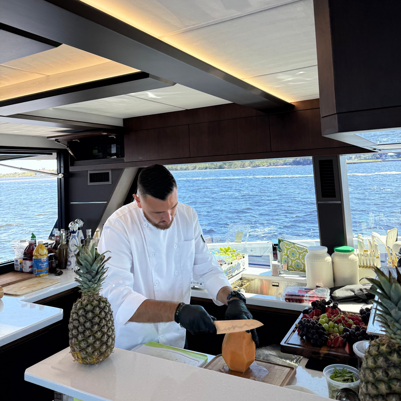private Chef preparing food in a kitchen with a view of water on a yacht