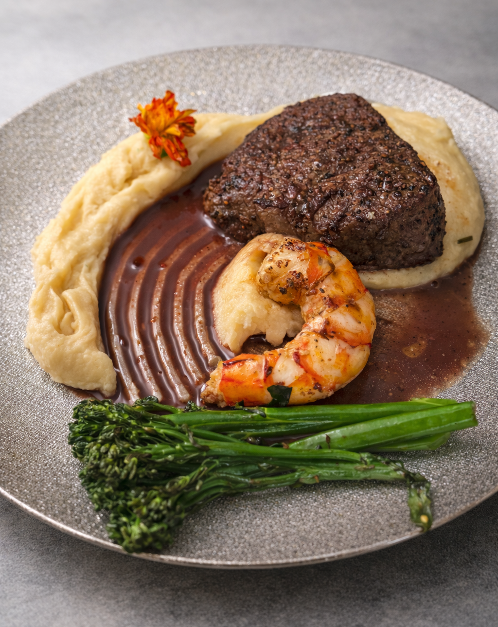 Dish with steak, shrimp, and vegetables on a gray plate